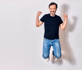 Middle age handsome man wearing casual clothes smiling happy. Jumping with smile on face doing...