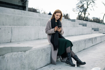 Pretty girl prints a message in a smartphone.