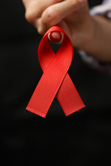 red ribbon on the finger on dark background