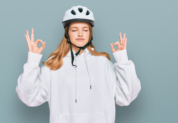 Beautiful young caucasian girl wearing bike helmet relax and smiling with eyes closed doing meditation gesture with fingers. yoga concept.