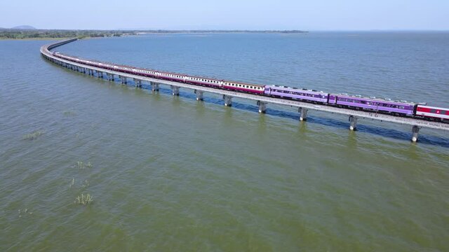 Aerial view of Thailand Excursion train run on the floating railway bridge with blue sky in the lake of "Pa Sak Jolasid dam" at Lopburi province Thailand