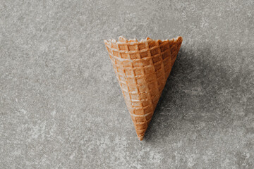 Empty waffle cone over a grey concrete background