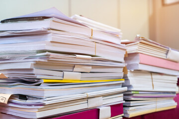 Pile of books and documents report papers waiting be managed on desk in busy office. Concept of workload in business finacial paperwork information planing