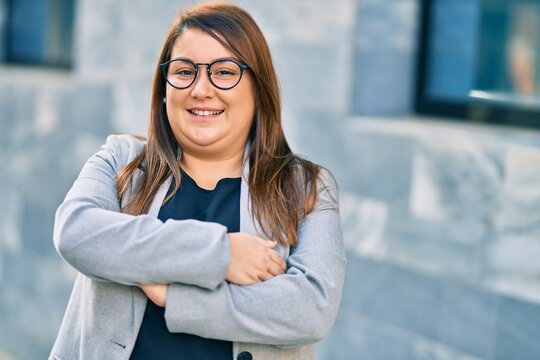 Young hispanic plus size businesswoman smiling happy standing at the city.