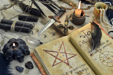 Fototapeta na wymiar Still life with black magic grimoire book, burning candles and ritual objects on witch table.