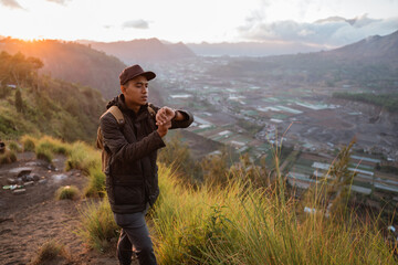 Portrait adventurous man with a backpack captures the moment. Beautiful mountain scenery in the morning