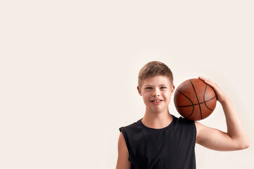 Portrait of cheerful disabled boy with Down syndrome smiling at camera while posing with basketball...