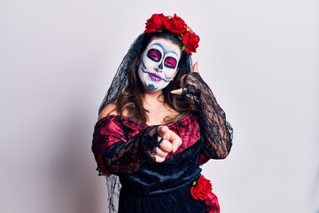 Young woman wearing day of the dead costume over white smiling doing talking on the telephone gesture and pointing to you. call me.