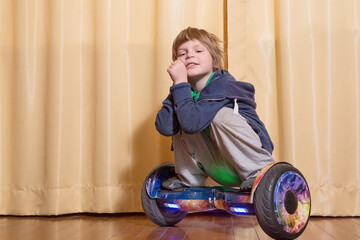 A boy, a European, 5 years old, stands on a hoverboard, looks at the camera, smiles.