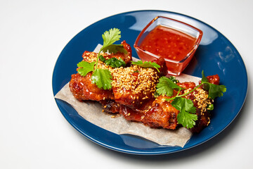 Sesame fried chicken wings with sauce and parsley. Close-up, selective focus