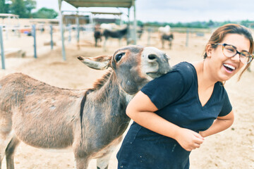 Hispanic woman playing with donkey at the farm.