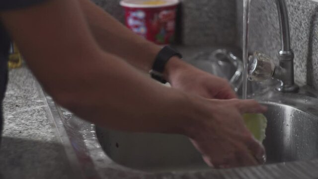 Person Hands With Running Tap Water Rinse And Cleaning Dirty Dishes. - Close Up