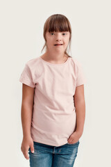 Obraz premium Portrait of disabled girl with Down syndrome looking at camera while posing isolated over white background