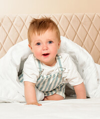 Fototapeta premium Happy cheerful baby in the interior of the bedroom. Laughter.