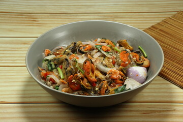 Spicy vermicelli salad mixed with steamed mussel, chilly and sliced shallot on the plate. Famous traditional appetizer menu in Asia restaurant. 