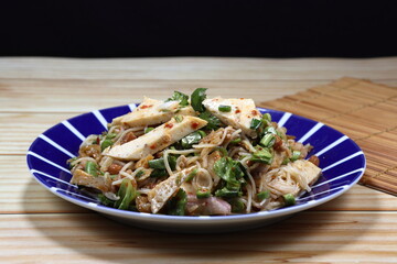 Spicy rice noodle mixed with Thai steamed pork sausage, chilly and local herbal vegetable seasoning with pickled fish sauce on the plate. Famous traditional appetizer menu in Asia restaurant. 