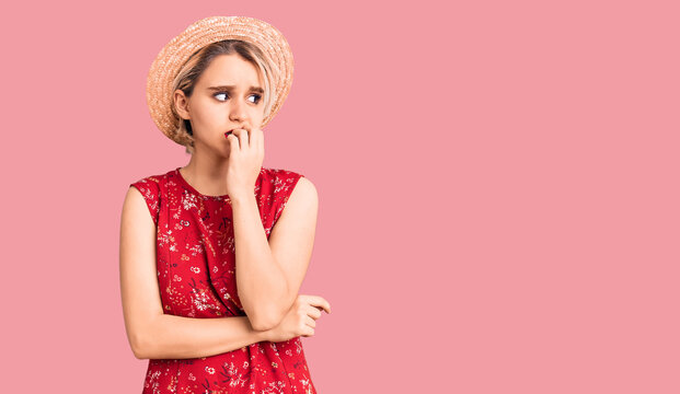 Young beautiful blonde woman wearing summer hat looking stressed and nervous with hands on mouth biting nails. anxiety problem.
