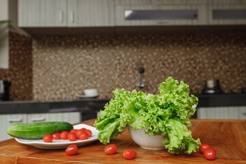  Fresh vegetables - cherry tomatoes, lettuce and cucumber on the cutting board at home kitchen. The concept of vegeterian food