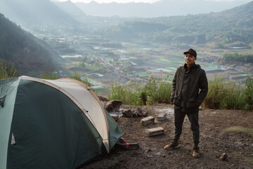 Fototapeta premium Portrait adventurous man camping captures the moment. Beautiful mountain scenery in the morning