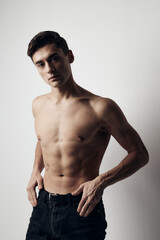 Fototapeta premium Muscular guy in pants nude torso cropped view over gray background