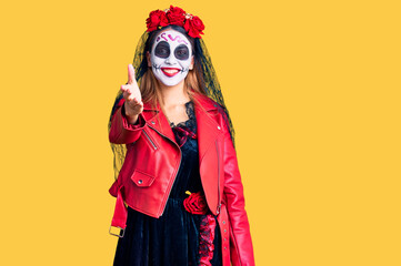 Woman wearing day of the dead costume over background smiling friendly offering handshake as greeting and welcoming. successful business.