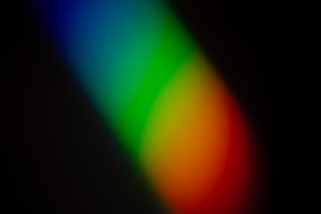 Clear and vibrant Rainbow color gradient reflect on a dark wall photograph.