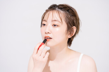 口紅を塗るアジア人の若い女性