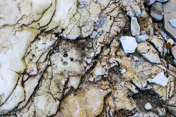 mountain textures of stones with interlayers of gypsum, colored quartz, clay, sand and other layers of various ores, with different textures, color and density, in gypsum ore quarry.