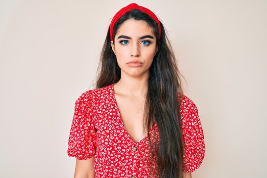 Brunette teenager girl wearing summer dress with serious expression on face. simple and natural looking at the camera.