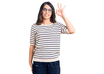 Obraz na płótnie Canvas Brunette teenager girl wearing casual clothes and glasses smiling positive doing ok sign with hand and fingers. successful expression.