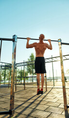 Muscular caucasian calisthenic athlete on horizontal bar