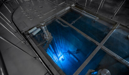 Blue glow water of nuclear reactor core powered, caused by Cherenkov radiation, fuel plates...