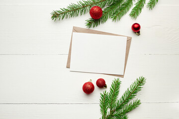 Fototapeta na wymiar Greeting card mockup with red christmas decorations and fir tree branches on white background