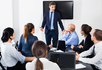 Friendly smiling manager making speech during business meeting in office