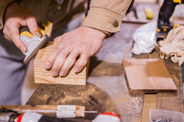 Close up of unrecognizable carpenter restoring a wood with sand paper