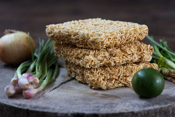 Instant Thai mama noodles on wooden board with Thai ingredients like lime, lemongrass, spring onions and onion