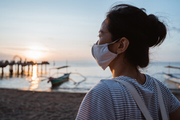 Woman visiting the beach with face mask for healthy in the sunny morning