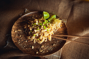 Chicken pad thai noodles with lime , mung bean sprouts and nuts on linen background
