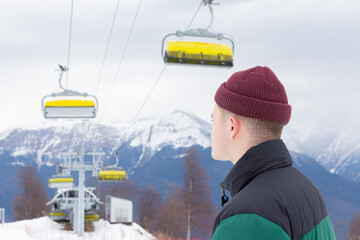 Ski resort. The young man admires nature, stands against the background of the mountains.