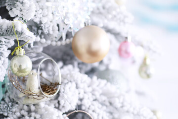 Christmas holiday background. Silver and color bauble hanging from a decorated on tree with bokeh and snow, copy space.