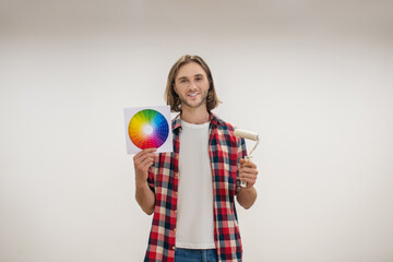 Young man holding a paint roller and a color palette