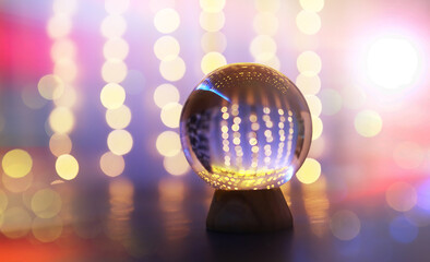 Crystal Ball on the floor with bokeh, lights behind. Glass ball with colorful bokeh light, celebration concept.