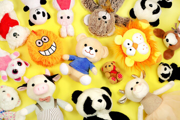 Many stuffed toys on yellow background, top view. 