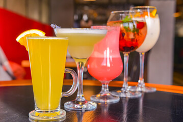 Cocktails on the table. Different coloured drinks in different glasses on dark wooden table.