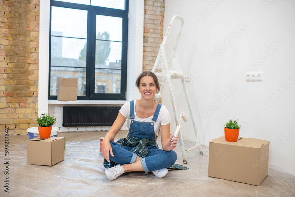 Wall mural young long-haired woman sitting on the floor and smiling