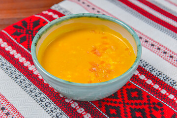 Pumpkin soup with fresh pumpkin seeds served in a bowl over traditional Ukrainian tablecloth. Ukrainian cuisine concept.