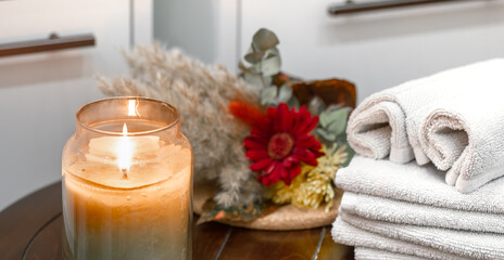Spa composition with burning candle and bath towels.