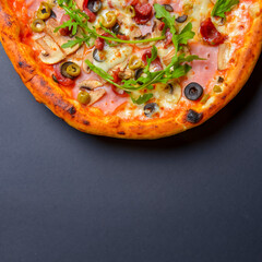 Hot tasty delicious rustic homemade american pizza over black background. Traditional Italian cuisine concept.