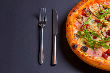 Hot tasty delicious rustic homemade american pizza over black background. Traditional Italian cuisine concept.