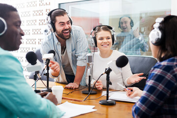 Smiling international team of radio hosts interviewing guest in sound broadcasting station